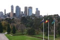 Urban park with trees, grass, flagpoles and iconic cityscape of modern skyscrapers in Melbourne downtown, Victoria, Australia Royalty Free Stock Photo