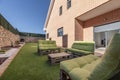 Garden of a single-family home with metal fence and stone ashlar, floors covered with artificial grass and pallet sofas with green Royalty Free Stock Photo