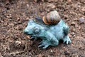 Garden snail crawls on a bronze frog. Mollusk and garden decoration. Royalty Free Stock Photo