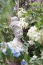 Garden statue. A beautiful stone statue of a woman with a turban and flowers on her hair in the mysteriously secret garden