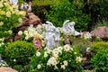 Garden statues of angels and birds on flowerbed