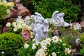 Garden statues of angels and birds on flowerbed