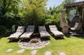 Garden sunbeds on green grass, bamboo fence background.