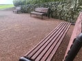 Garden with three benches, rocks wall and boxwood bushes.