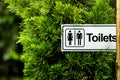 Garden toilet sign with green pines.