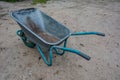 Dirty metal garden wheelbarrow on bare ground Royalty Free Stock Photo