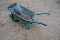 Dirty metal garden wheelbarrow on bare ground Royalty Free Stock Photo