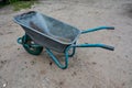 Dirty metal garden wheelbarrow on bare ground Royalty Free Stock Photo