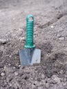 A garden trowel sticking out of a pile of soil