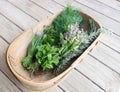 Garden trug of fresh organic herbs on wooden deck: chives, mint, thyme, sage, rosemary, dill