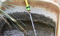 Garden water yellow and green hose pouring water into an old bucket Royalty Free Stock Photo