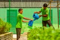 Garden worker in the uniform watering plants using water cans