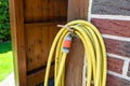 A garden yellow hose connected to a tap protruding from a farm building against a background of brick facade, visible plastic wate Royalty Free Stock Photo