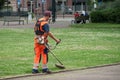 Gardener with Brush cutter in urban park