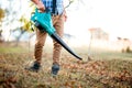 Man Gardener clearing up leaves using an electric leaf blower tool. Gardening details