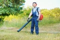 Gardener clearing up the leaves using a leaf blower Royalty Free Stock Photo