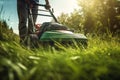 Gardener cutting grass lawn with electric cordless mower. Man trimming grass with lawn mower on sunny weather. Generative AI