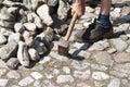 a gardener in dirty work clothes and boots holds a two-bladed iron hammer Royalty Free Stock Photo