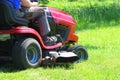 Gardener driving a riding lawn mower in a garden Royalty Free Stock Photo