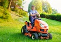 Gardener driving a riding lawn mower in garden