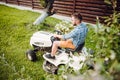 Gardener driving a riding lawn mower in a garden. Royalty Free Stock Photo