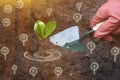 Gardener grows plant seedling. Green Shovel in hand. Nutrients for cultivated plants in soil. Concept of agricultural industry,