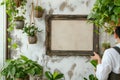 gardener hangs an empty rustic frame on a wall beside indoor hanging planters