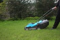 The gardener holds the handle of the lawn mower. Lawn mowing