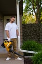 Gardener man clearing up the leaves using a leaf blower tool Royalty Free Stock Photo
