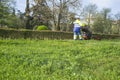 Gardener mowing the grass with engine powered mower at urban par