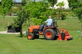 Gardener mowing lawn, Alrewas, UK.