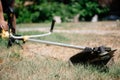 Gardener mows the grass with a trimmer in the yard in the summer Royalty Free Stock Photo