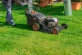 The gardener mows the lawn with a lawn mower