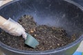 Gardener old women use plastic grove in hand holding green spade for mixing soil and fertilizer in black plastic circle pot