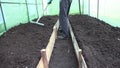 Gardener prepare soil bed with raker tool in hothouse. 4K