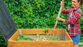 A gardener prepares compost from food organic waste in a DIY wooden compost bin. Zero waste concept. Aging of compost for its