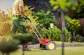 Gardener with Push Spreader Fertilizing Residential Grass Lawn