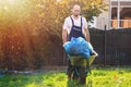 The gardener rolls a cart with bags of leaves. Cleaning the yard. The sun is shining on the left side