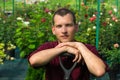 Gardener stands in a greenhouse against a background of various plants