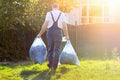 Gardener in uniform carries compost in bags after cleaning the ground.the employee in the sunlight