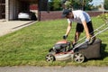 Gardener unscrews the gasoline cap of the lawn mower to fill the fuel tank.