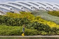 Gardener walking along flowerbeds with the Flower Dome in the background