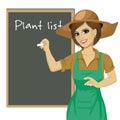 Gardener woman in green overalls writing down list of plants on blackboard