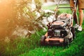 Gardening details, industrial gardener using lawnmower and cutting grass