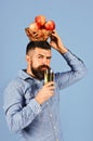 Gardening and fall crops concept. Farmer with serious face holds juice and apples on head Royalty Free Stock Photo