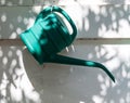 Gardening objects. Green plastic two liters hand watering can  is hanging on white wall Royalty Free Stock Photo