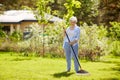 Senior woman with lawn rake working at garden