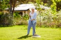 Senior woman with lawn rake working at garden