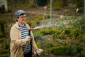 Gardening and people concept - happy senior woman watering lawn by garden hose at summer Royalty Free Stock Photo