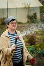 Gardening and people concept - happy senior woman watering lawn by garden hose at summer Royalty Free Stock Photo